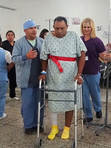 A patient in Guatemala walking with support after free joint-replacement surgery